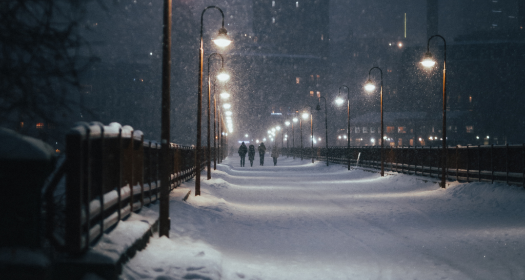 Via piena di neve con lampioni e persone che camminano vestite pesantemente
