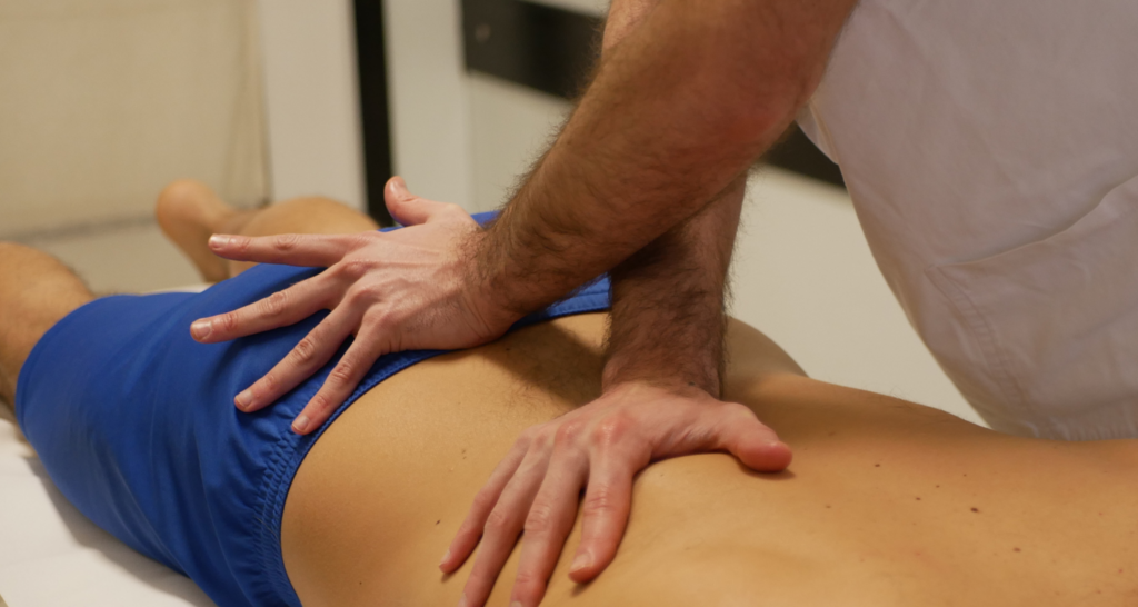 Osteopata che tratta a paziente sdraiato muscoli della schiena