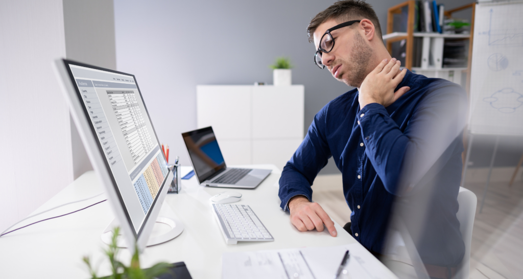 Uomo davanti a PC che si tocca la cervicale con segno di dolore