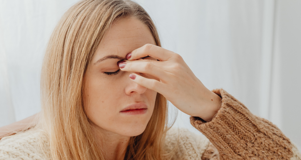 Ragazza che si tocca tra occhio e naso con segno di dolore intenso e invalidante