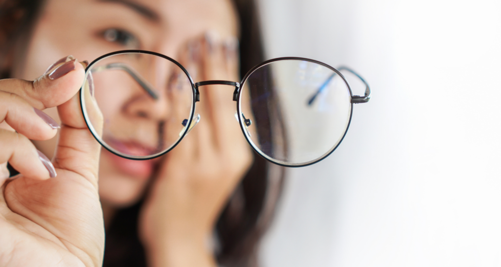 ragazza che guarda gli occhiali mentre si tocca occhio affaticato