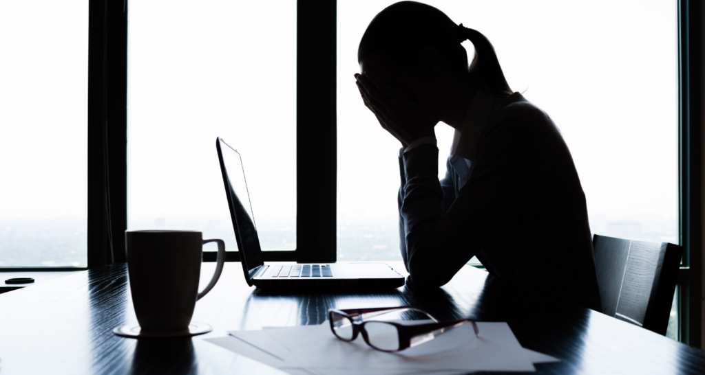 giovane donna al pc che si mette le mani in faccia in segno di burn-out